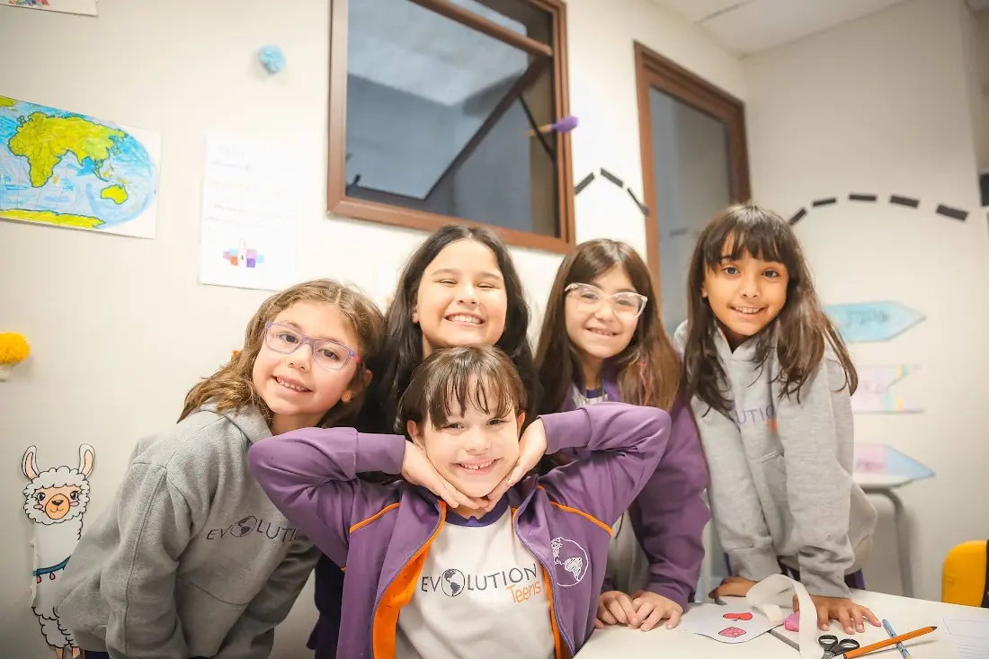 Grupo de alunas da Evolution abraçadas e sorrindo em sala