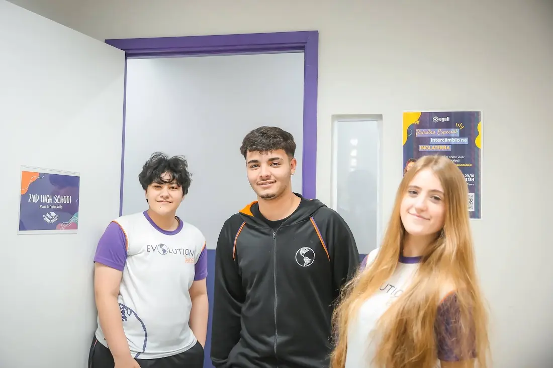 Três alunos do Ensino Médio da Evolution Teens em frente ao mural do High School
